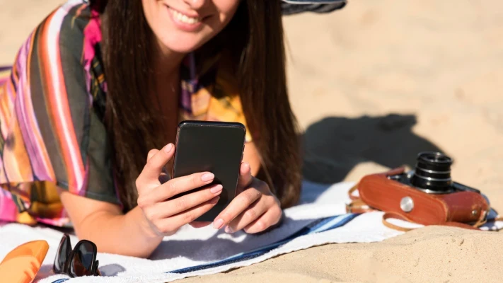 Detailní pohled na ženu na pláži hledící do mobilního telefonu